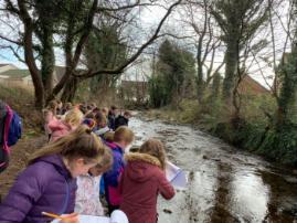 School children taking notes next to a river