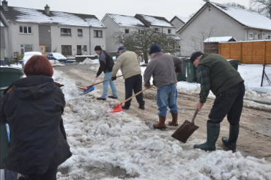 4 people shovelling snow out of the road